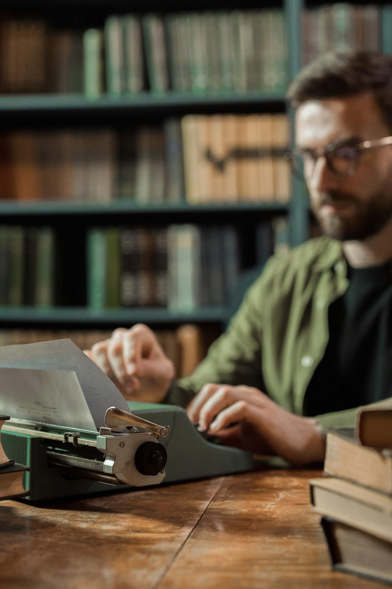 A man typing on a vintage typewriter in a cozy library setting.